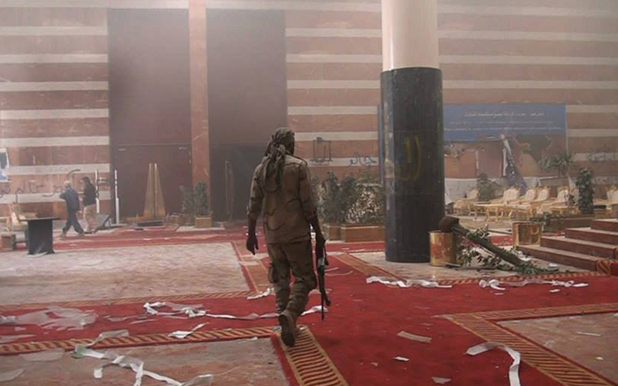 A man in fatigues walking through a ruined hall in Libya